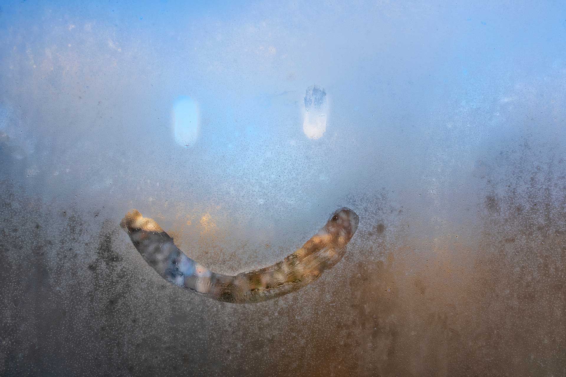 Smiley face drawn on foggy window